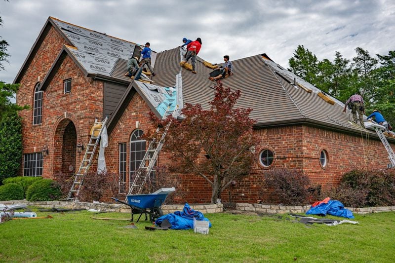Roofing crew tearing off old shingles during a roof replacement in Akron, OH